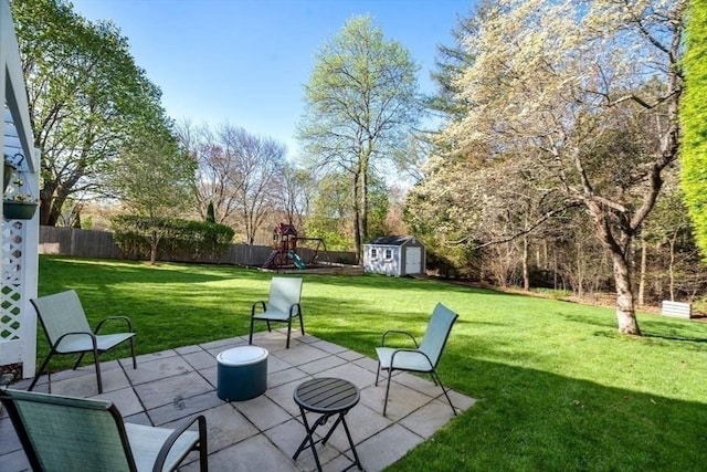 view of patio / terrace featuring a fenced backyard, a playground, a shed, and an outbuilding