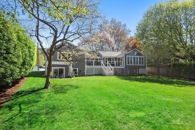 back of house featuring stairway, a lawn, fence, and a sunroom