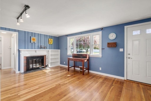 living room featuring a healthy amount of sunlight, baseboards, a fireplace, and wood finished floors