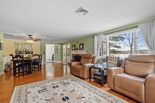407 Mountain Rd, Jaffrey, NH 03452 - living area featuring a textured ceiling, visible vents, ceiling fan, wood finished floors, and a stone fireplace