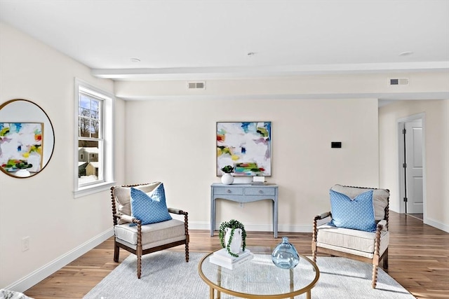 sitting room with visible vents, baseboards, and wood finished floors