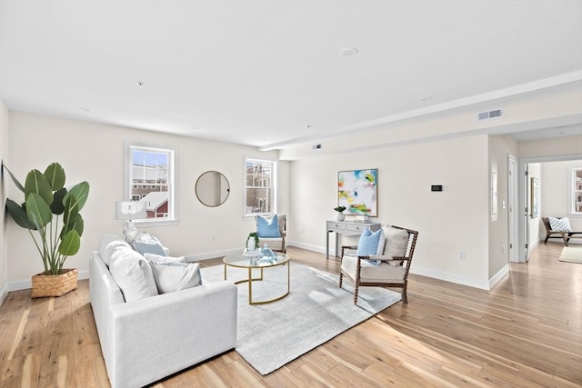 living area with baseboards, visible vents, and light wood-style floors