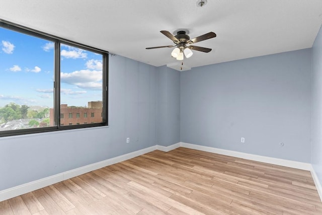 empty room featuring light wood finished floors, a ceiling fan, and baseboards