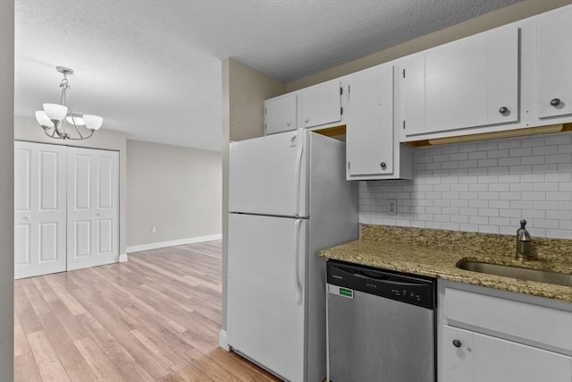 kitchen with stainless steel dishwasher, freestanding refrigerator, a sink, white cabinetry, and decorative backsplash