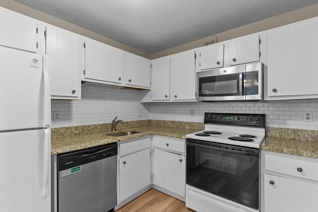 kitchen with stainless steel appliances, a sink, light wood-type flooring, backsplash, and a textured ceiling