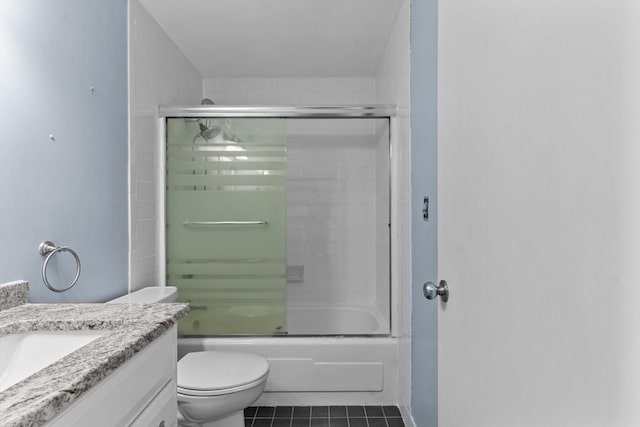 bathroom with tile patterned flooring, vanity, enclosed tub / shower combo, and toilet