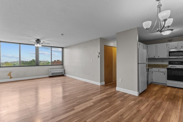 kitchen featuring stainless steel microwave, electric range oven, freestanding refrigerator, radiator, and wood finished floors