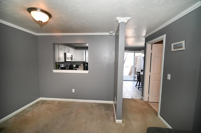 carpeted empty room featuring baseboards, ornamental molding, and a textured ceiling