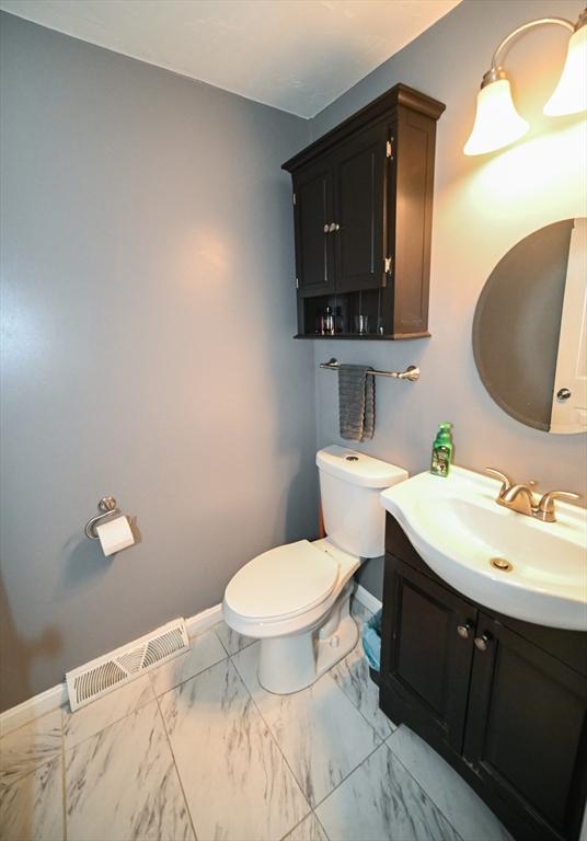 bathroom featuring toilet, baseboards, visible vents, and vanity