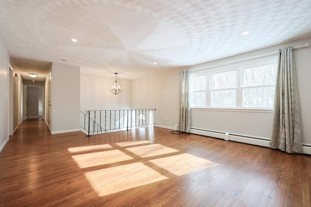 empty room with hardwood / wood-style flooring, a notable chandelier, and a textured ceiling