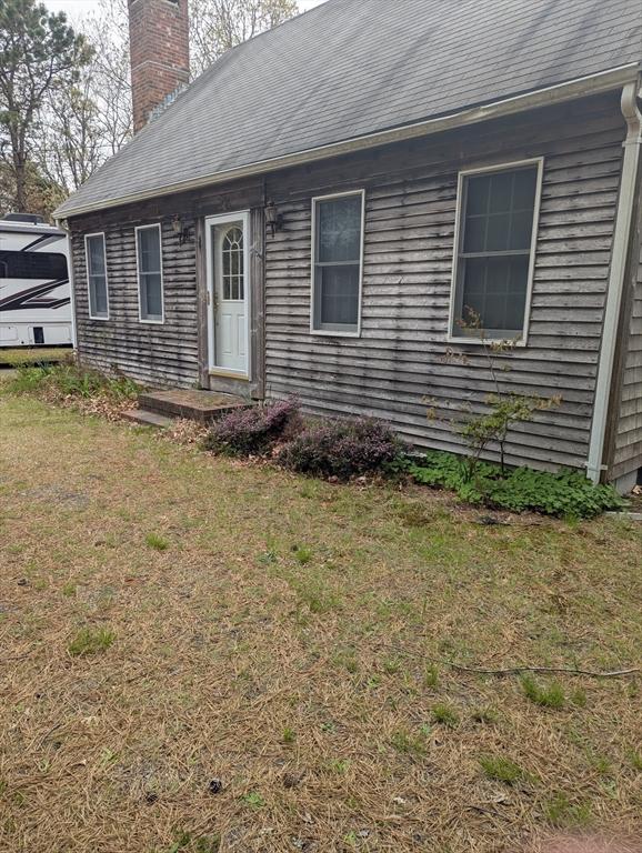 255 Massasoit Rd, Eastham, MA 02642 - rear view of property featuring a chimney, a yard, and roof with shingles