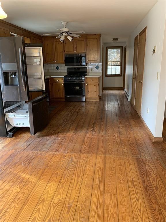 255 Massasoit Rd, Eastham, MA 02642 - kitchen featuring gas range, a ceiling fan, a baseboard heating unit, backsplash, and wood finished floors