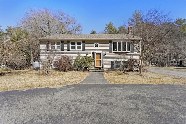 split foyer home with driveway and a chimney