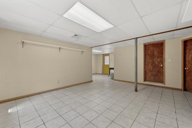 finished basement with light tile patterned floors, a paneled ceiling, and baseboards