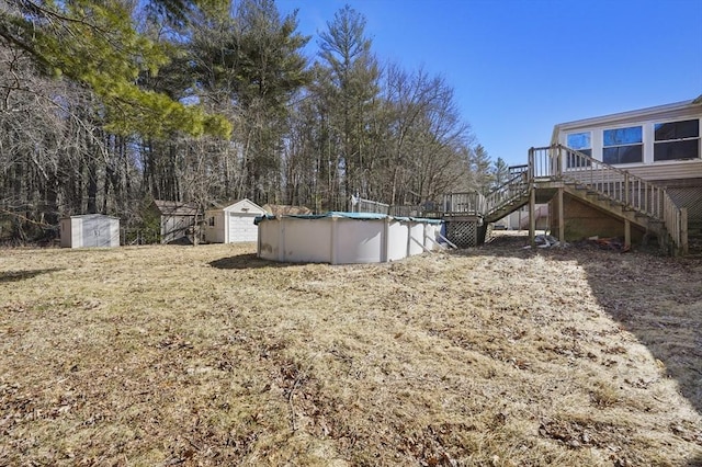 view of yard featuring an outdoor pool, stairs, an outdoor structure, a storage unit, and a deck