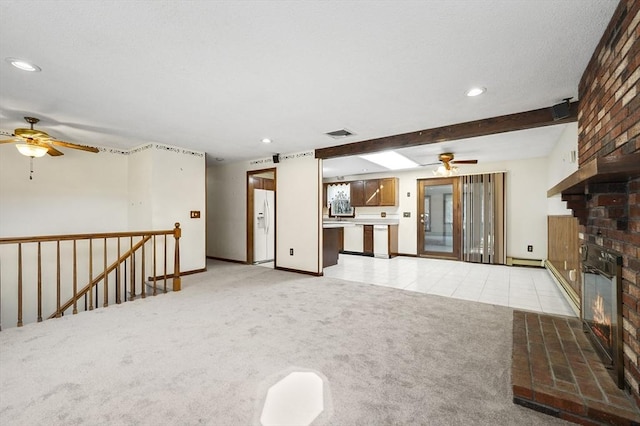 unfurnished living room with light tile patterned floors, visible vents, ceiling fan, a brick fireplace, and light colored carpet