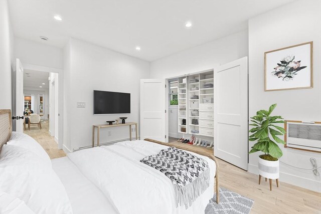 unfurnished bedroom featuring a baseboard heating unit, an AC wall unit, and light hardwood / wood-style floors