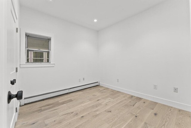 empty room featuring hardwood / wood-style flooring and baseboard heating