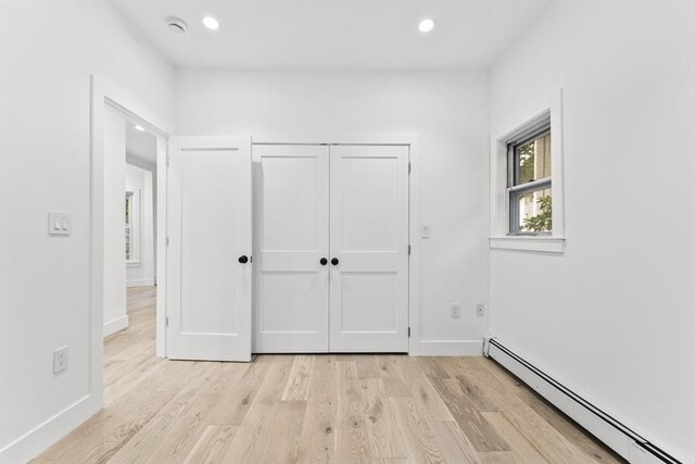 unfurnished bedroom featuring light hardwood / wood-style flooring and baseboard heating