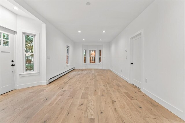 tiled empty room with a baseboard radiator and plenty of natural light