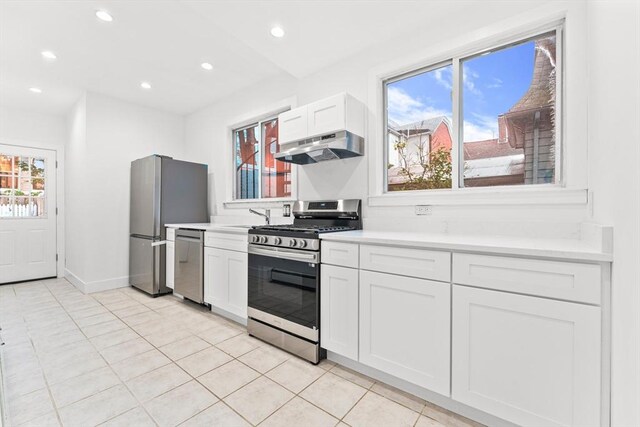 kitchen featuring light brown cabinetry, range with two ovens, dishwasher, and light tile patterned floors