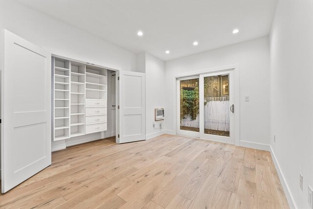 bedroom with light hardwood / wood-style floors and a wall mounted air conditioner