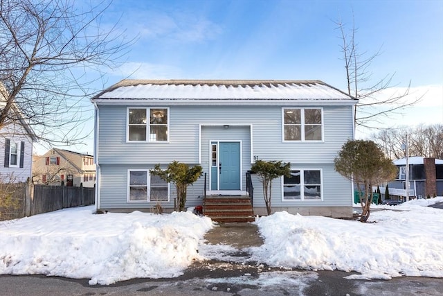 split foyer home with entry steps, fence, and metal roof