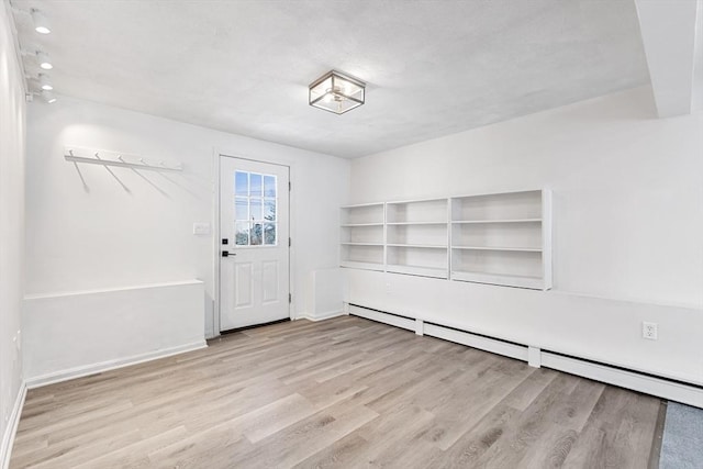 interior space with light wood-type flooring, a baseboard radiator, and baseboards