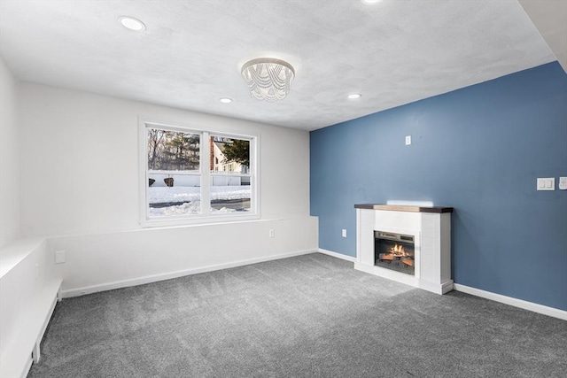 unfurnished living room featuring a lit fireplace, dark colored carpet, recessed lighting, and baseboards