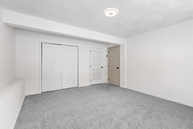 unfurnished bedroom with light carpet, baseboards, and a closet