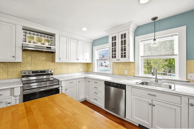 kitchen featuring stainless steel appliances, a sink, wooden counters, white cabinetry, and glass insert cabinets