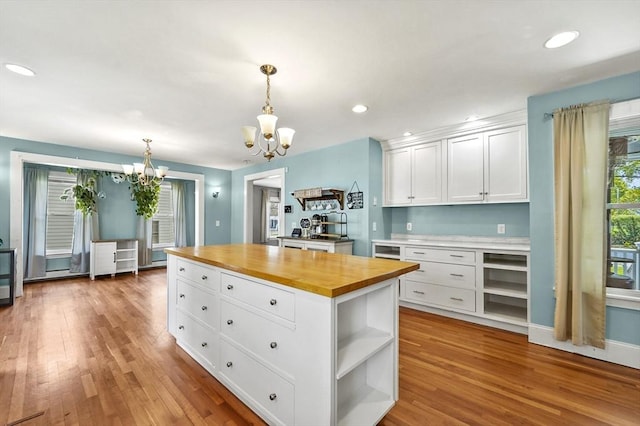 kitchen featuring butcher block counters, a chandelier, open shelves, white cabinetry, and wood finished floors