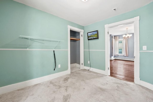 unfurnished bedroom featuring a chandelier, baseboards, carpet flooring, a baseboard radiator, and a closet