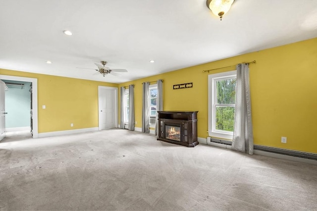 unfurnished living room with a glass covered fireplace, carpet, baseboards, recessed lighting, and ceiling fan