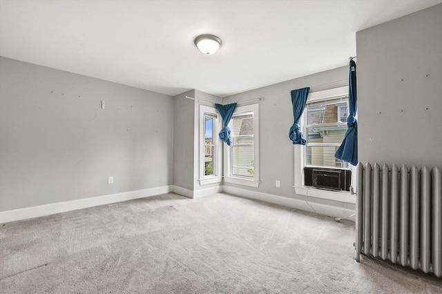 carpeted empty room with radiator and baseboards