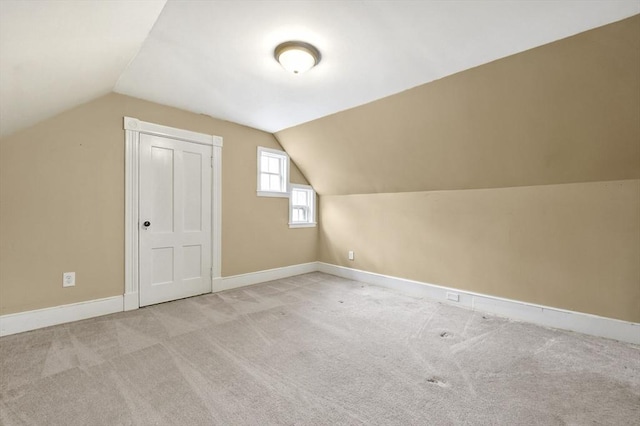 additional living space with light colored carpet, baseboards, and vaulted ceiling