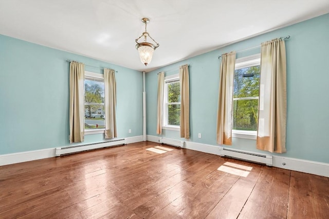 unfurnished room with baseboard heating, hardwood / wood-style floors, and baseboards