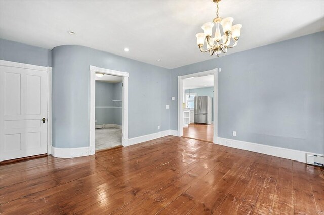 unfurnished dining area featuring a chandelier, hardwood / wood-style flooring, baseboards, and recessed lighting