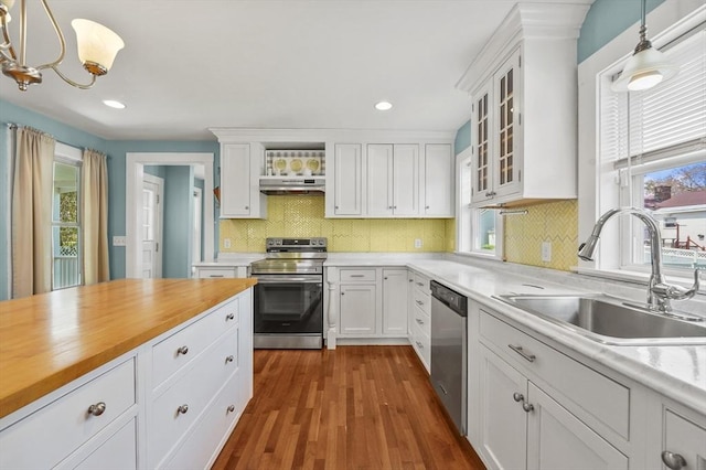 kitchen with stainless steel appliances, a sink, white cabinets, under cabinet range hood, and recessed lighting