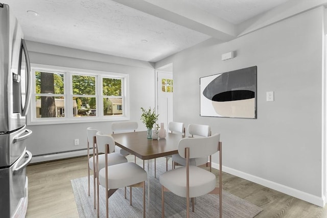 dining area featuring a textured ceiling, baseboards, light wood finished floors, and baseboard heating