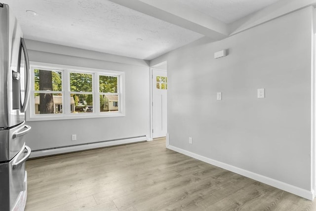 spare room featuring baseboard heating, a textured ceiling, wood finished floors, and baseboards