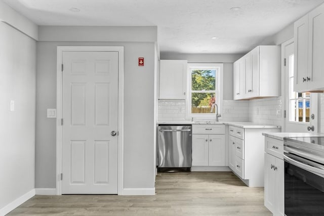 kitchen featuring white cabinets, tasteful backsplash, light countertops, and appliances with stainless steel finishes