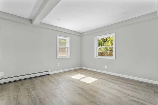 unfurnished room with beamed ceiling, baseboards, plenty of natural light, and wood finished floors