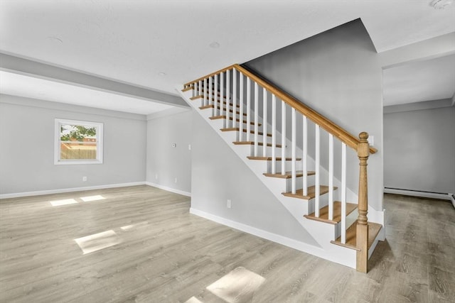 stairs featuring baseboard heating, wood finished floors, and baseboards