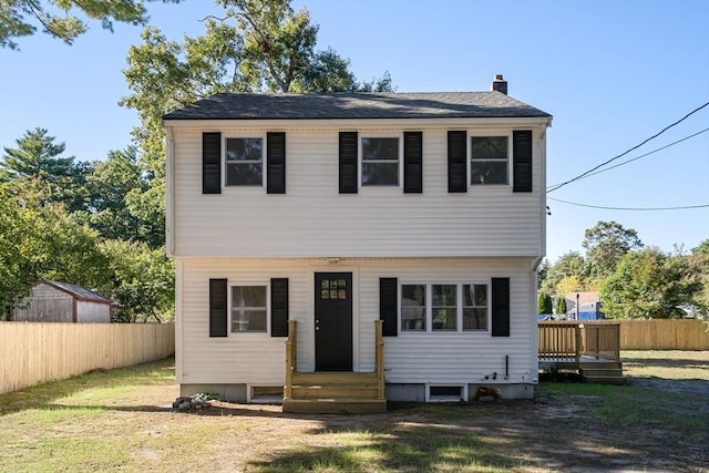 colonial house with a front lawn, fence, and a chimney
