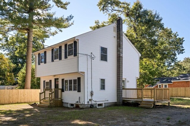 rear view of property featuring a deck, a chimney, and fence