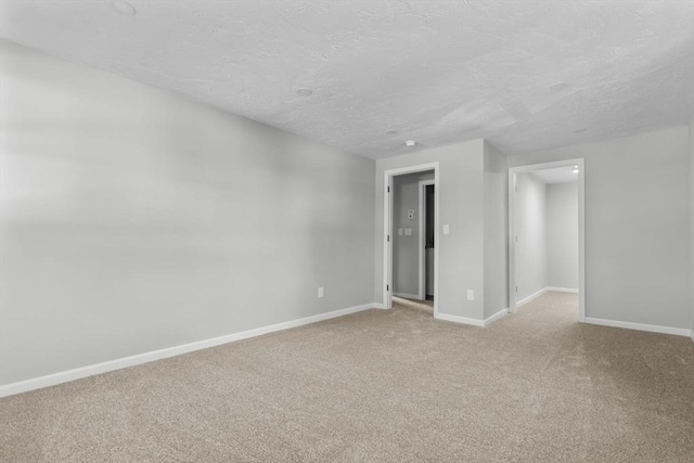 unfurnished room featuring light carpet, baseboards, and a textured ceiling