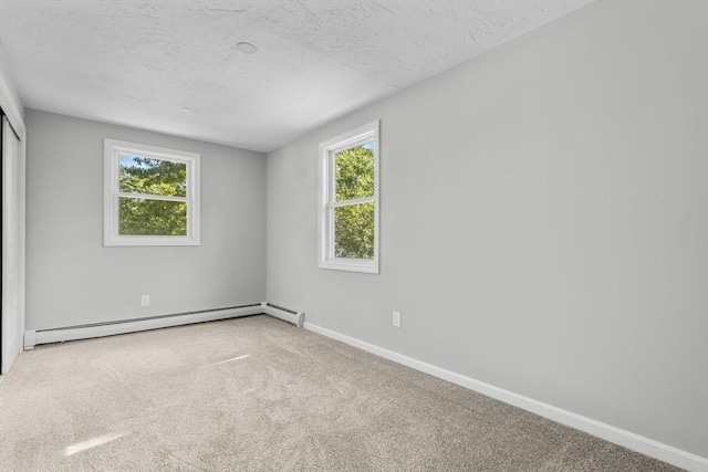 spare room featuring baseboard heating, a textured ceiling, baseboards, and carpet floors