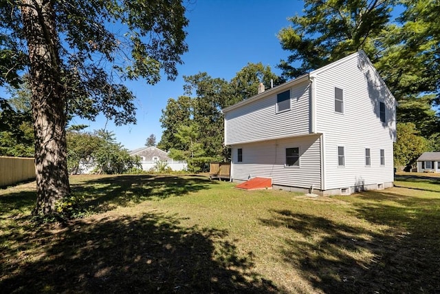 rear view of property featuring fence and a lawn