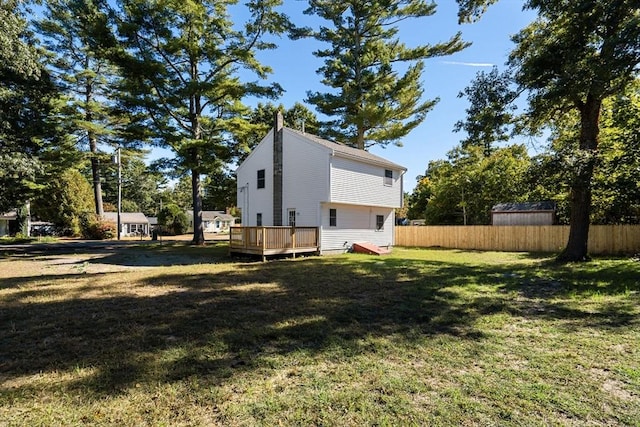 view of property exterior with a wooden deck, fence, and a lawn